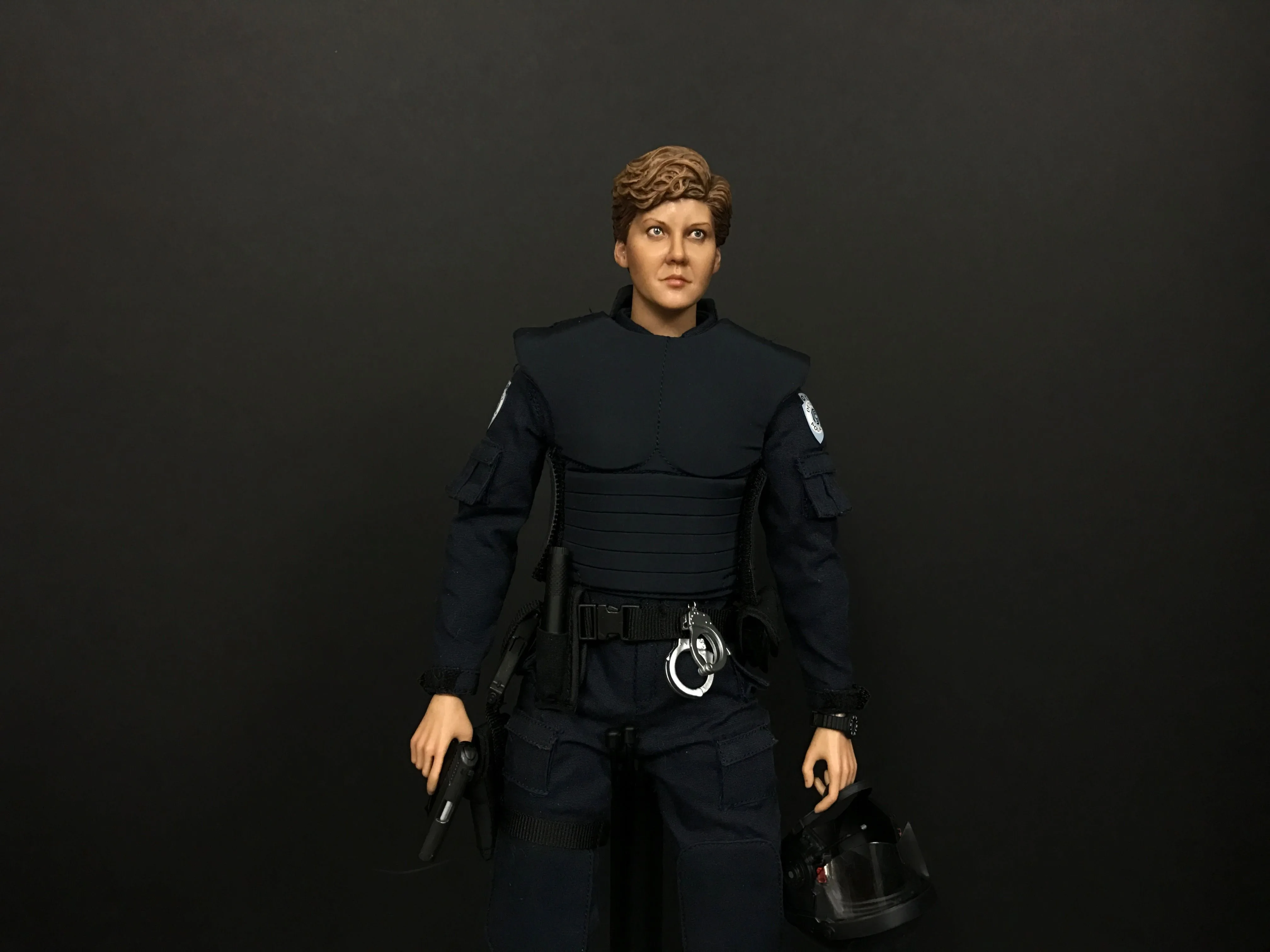 Custom Anne Lewis figure in a dark police uniform, holding a handgun at her side and a helmet in her other hand.
