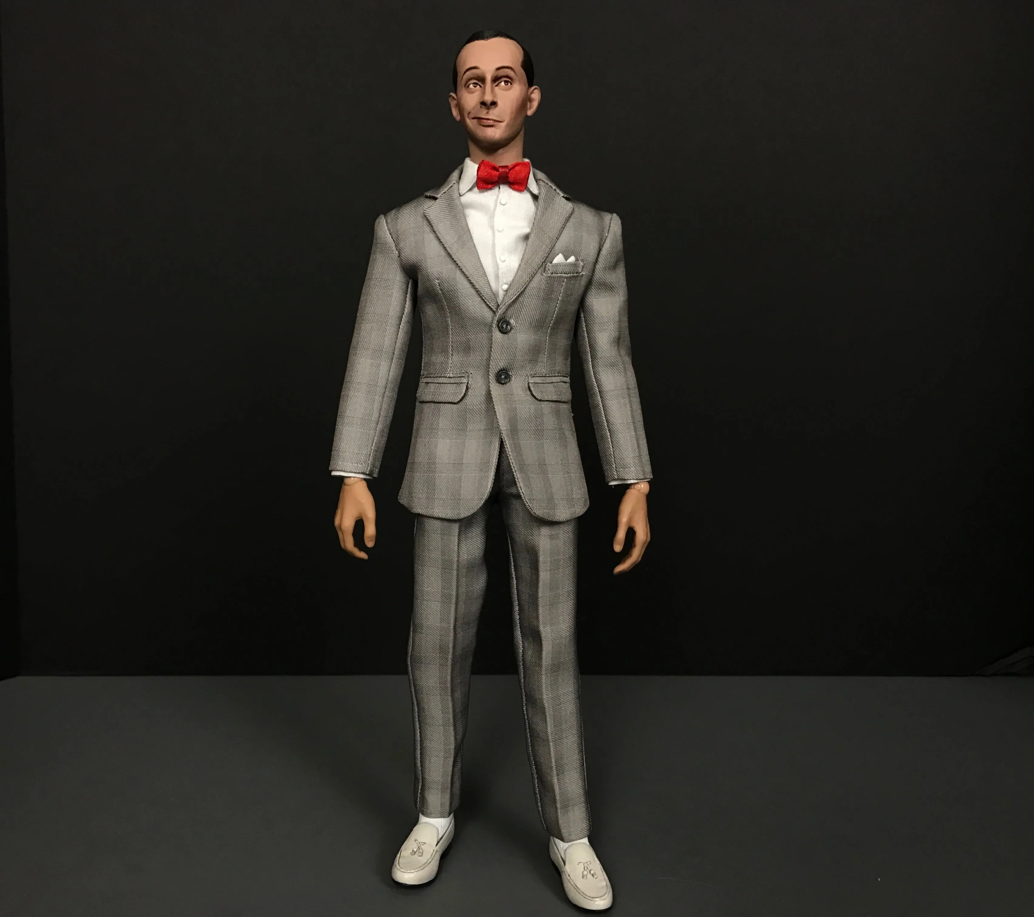 Full-length view of the custom Pee-wee Herman figure in a fitted gray plaid suit, red bow tie and white shoes.