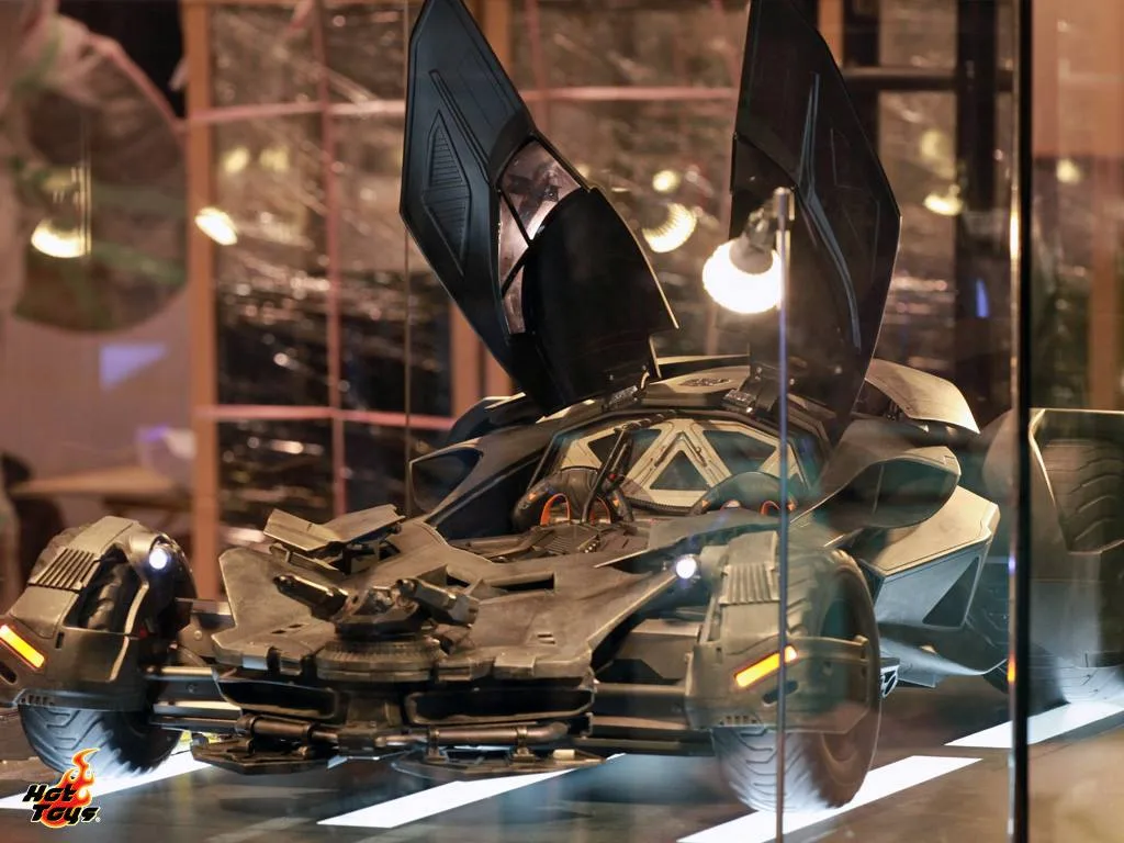Hot Toys Batman v Superman Batmobile on display behind glass with its canopy panels raised and front lights illuminated.