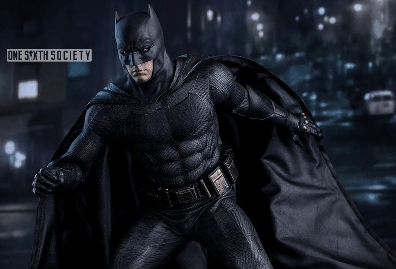 Hot Toys Batman figure leaning forward with one fist raised, showing his textured gray suit, black bat emblem and utility belt.