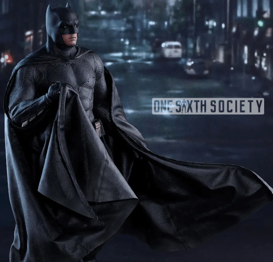 Batman figure standing with one hand gathering his cape at chest level while the remaining fabric trails to the side.