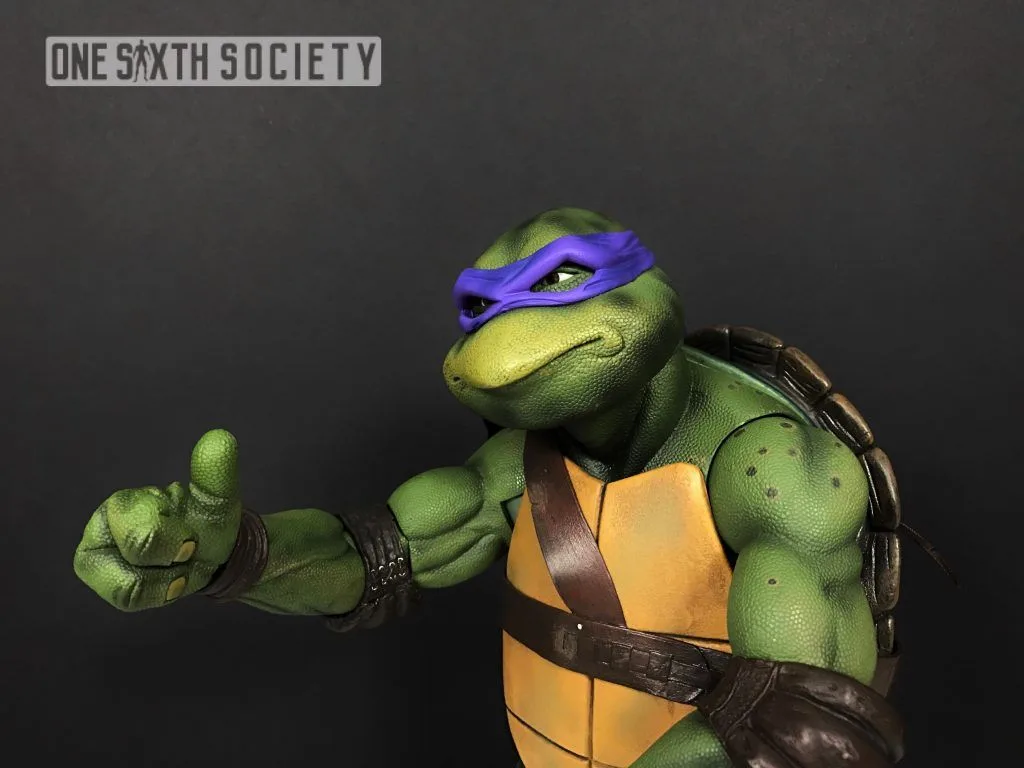 NECA Donatello extending a thumbs-up toward the camera, with his head turned slightly and the edge of his back shell visible.