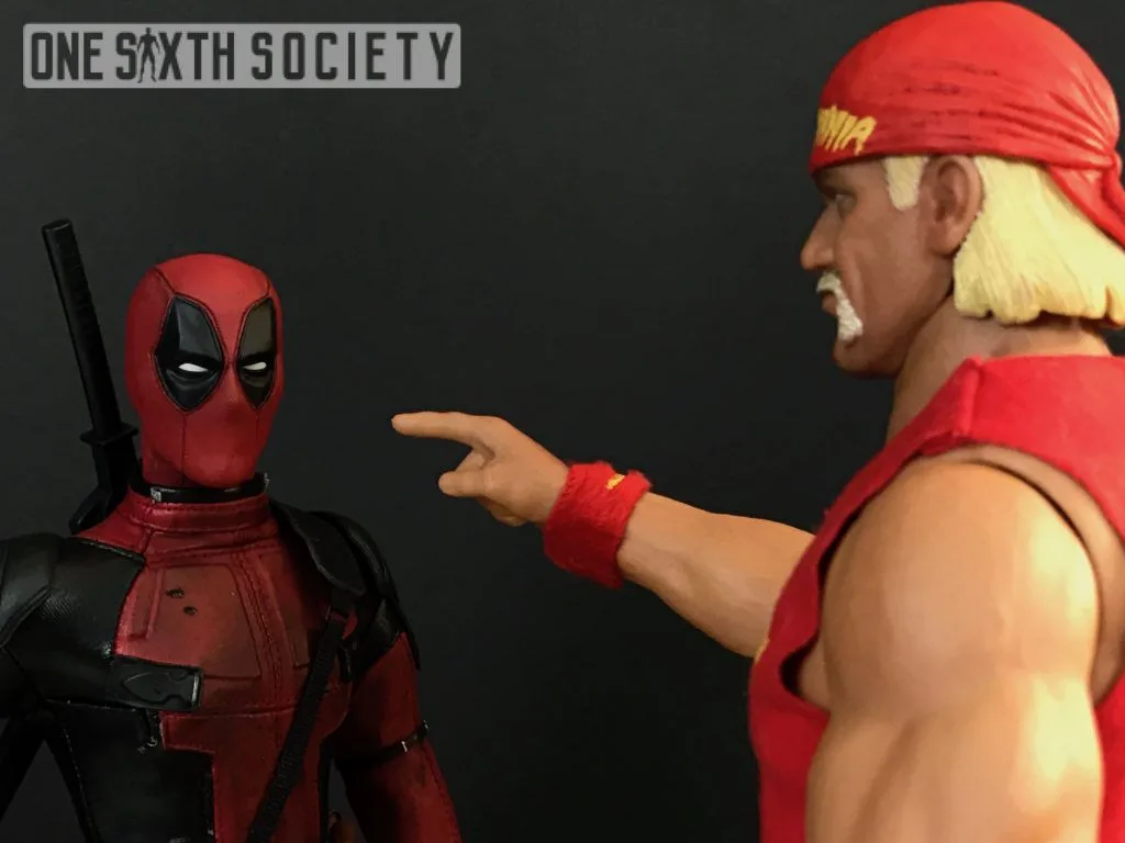 Hulk Hogan figure in a red bandanna pointing a finger toward Deadpool in a staged collectible scene.