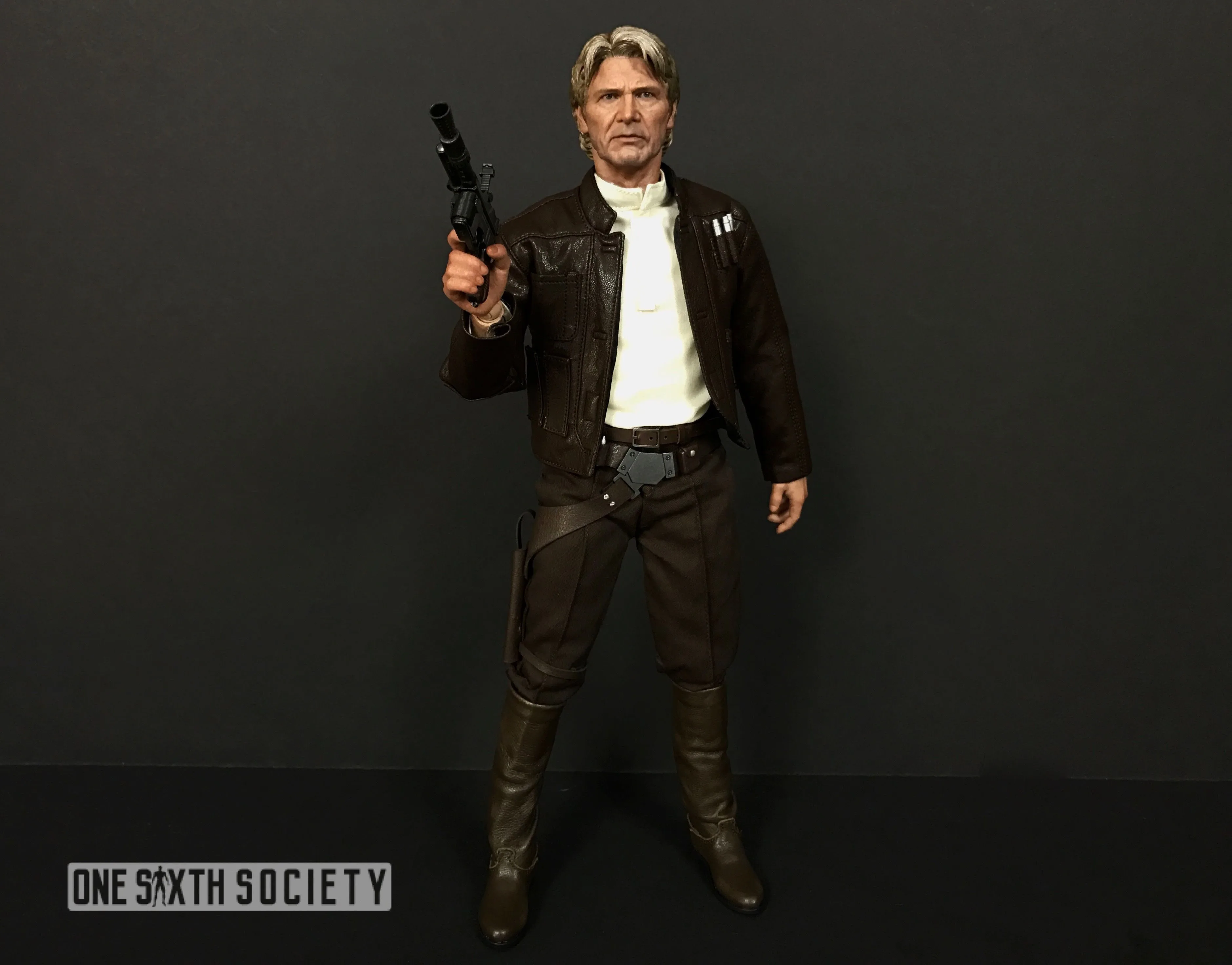 Full-length Hot Toys Han Solo in a brown jacket, cream shirt and dark trousers, holding his blaster upright.