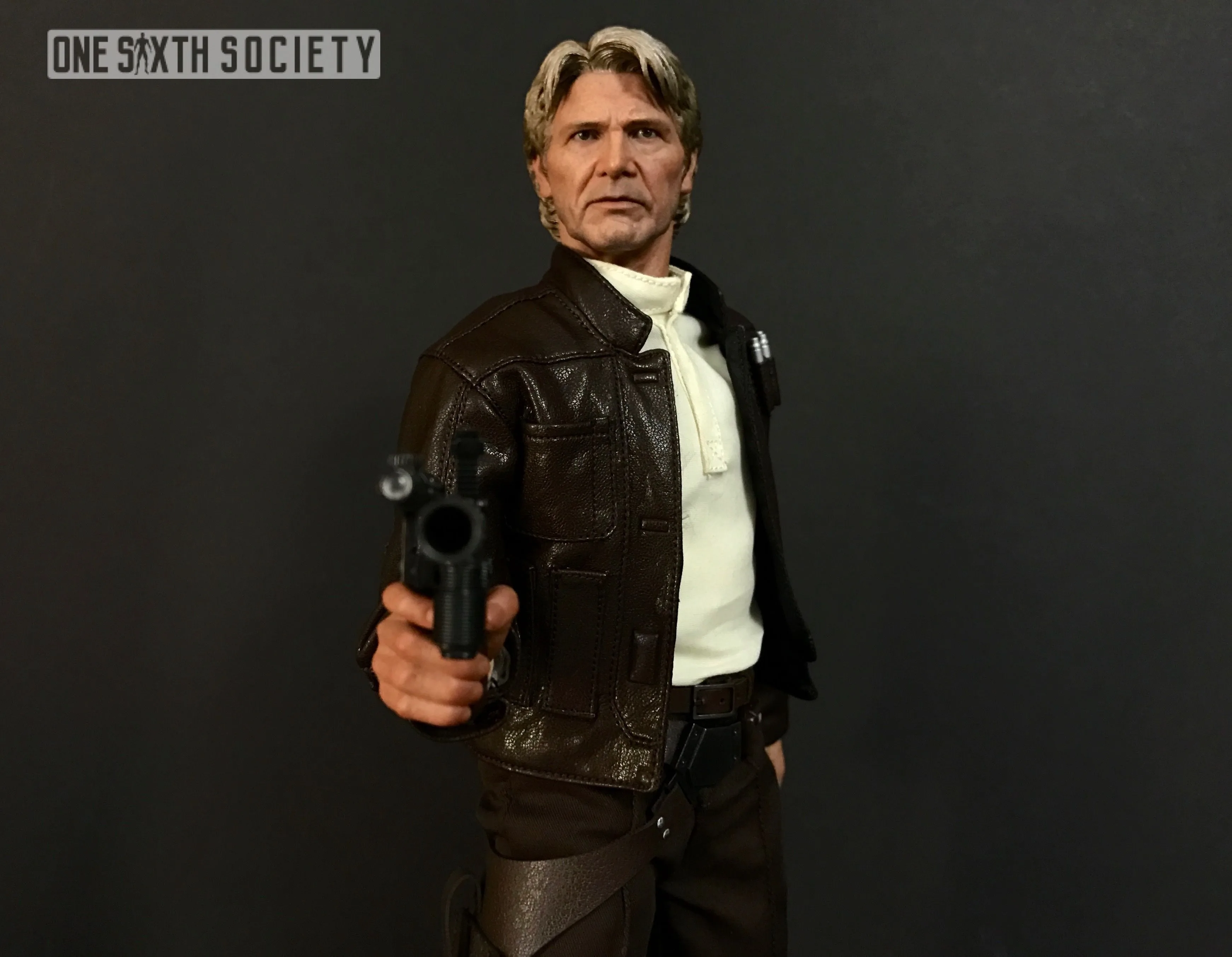 Waist-up view of Hot Toys Han Solo in his brown jacket, pointing a black blaster toward the camera.
