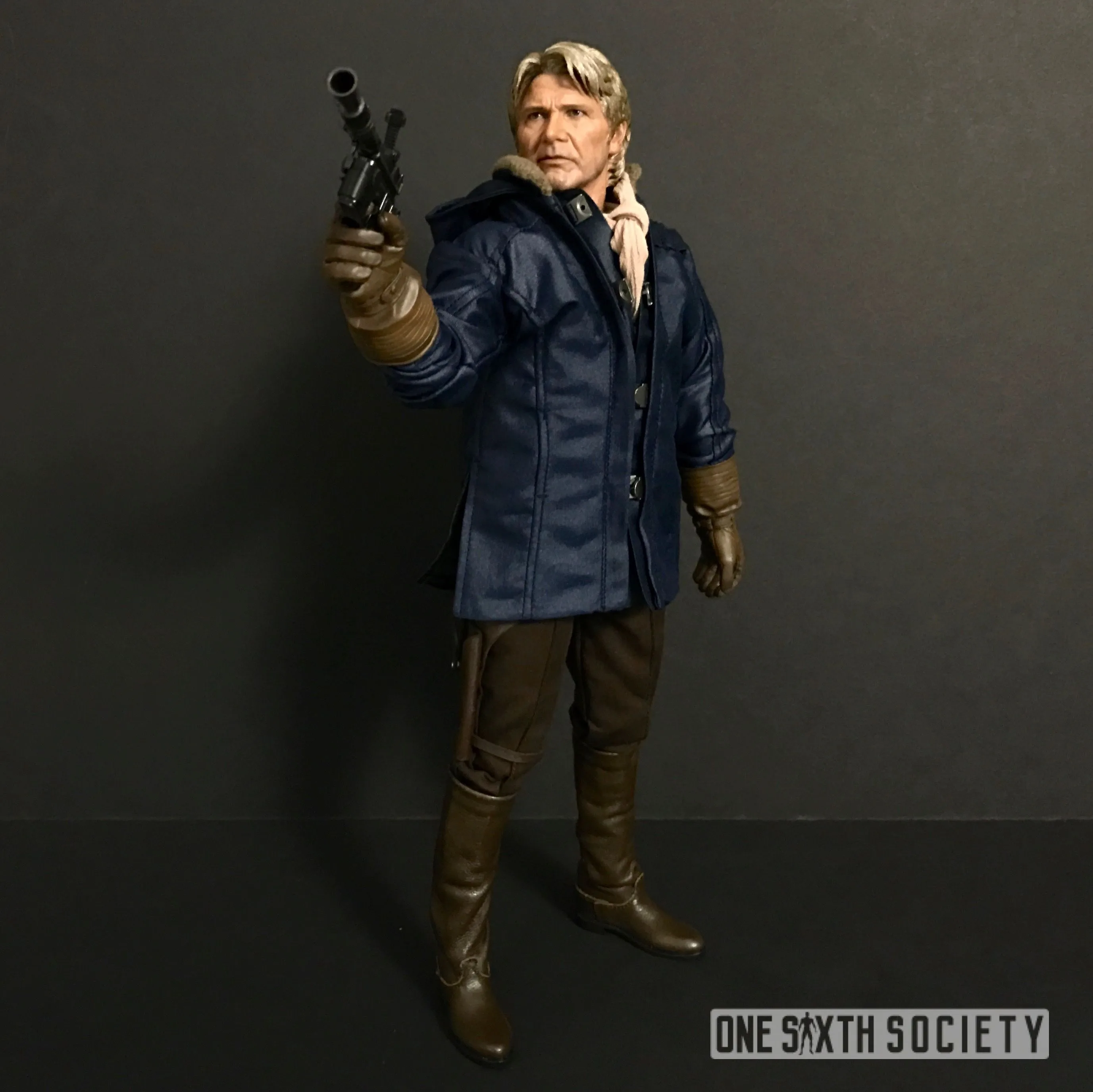 Hot Toys Han Solo wearing a blue winter coat, beige scarf and gloves while aiming his blaster to the side.