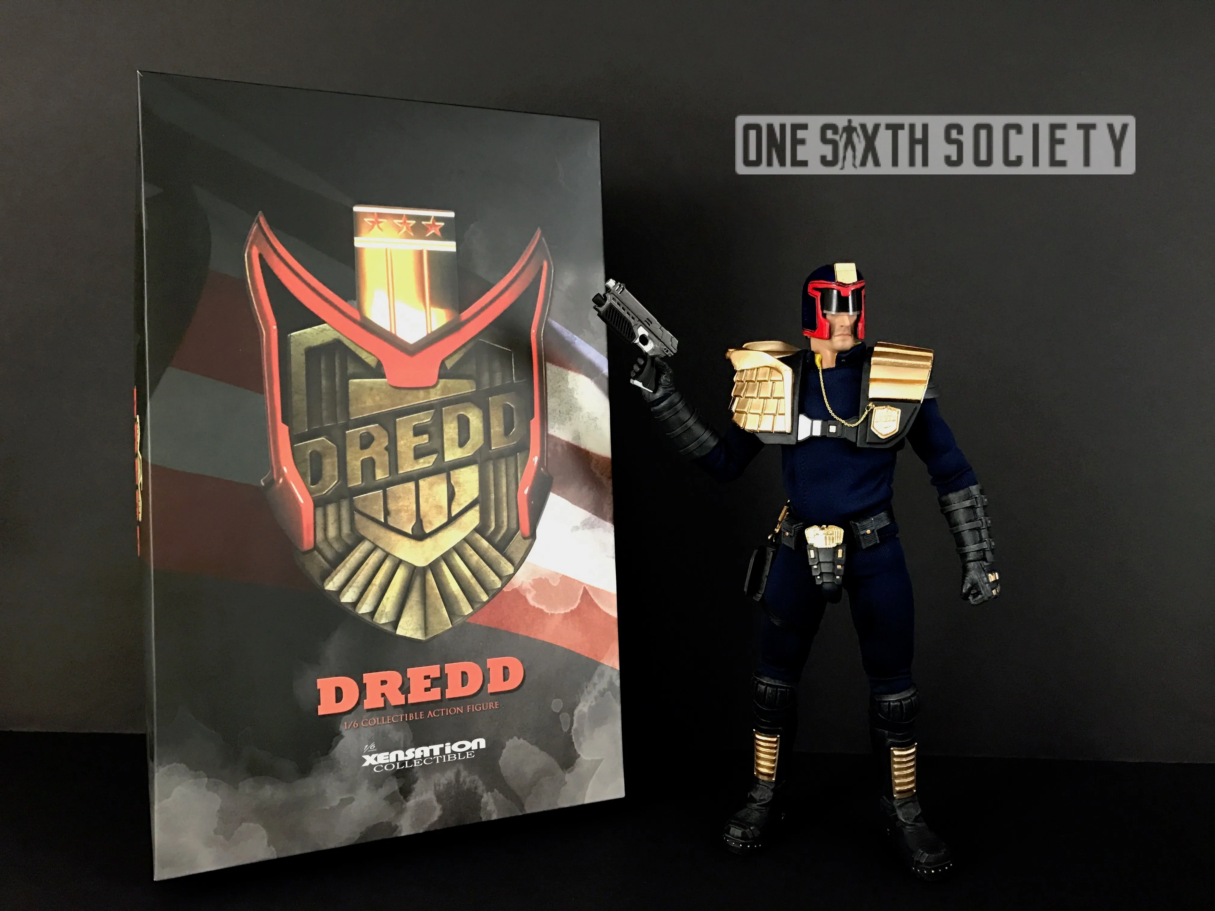 Xensation Judge Dredd figure holding a pistol upright beside packaging decorated with a large gold Dredd badge.