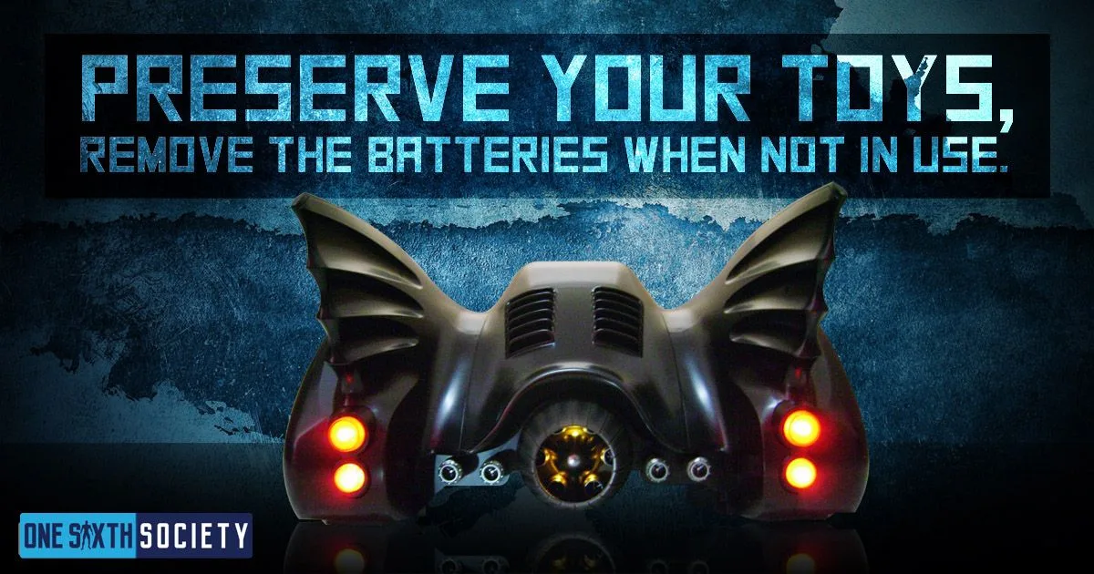 Rear of a Batmobile collectible with glowing red and yellow lights beneath a reminder to remove batteries when not in use.