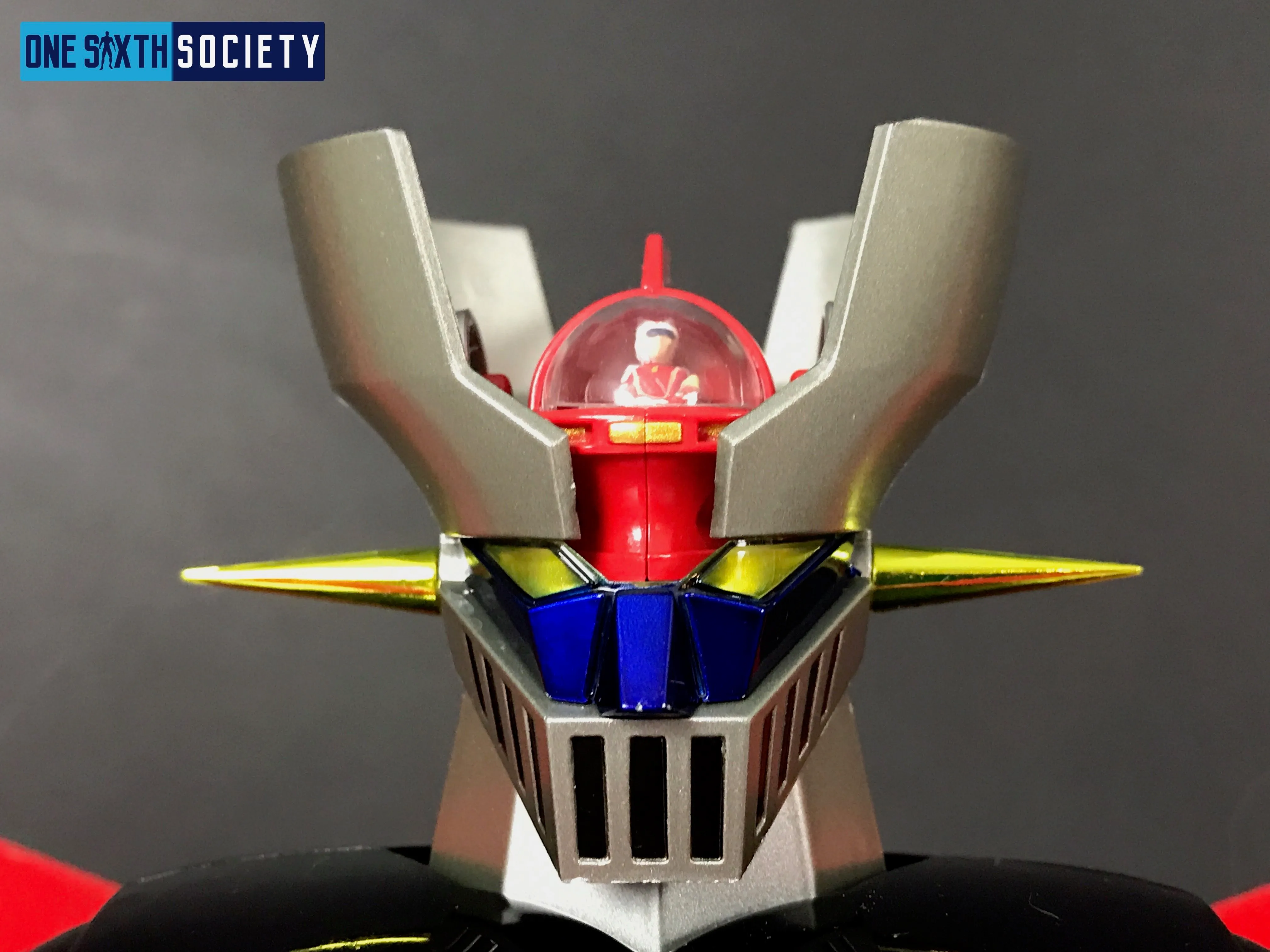 Close-up of Mazinger Z's silver head fins, yellow eyes, blue face details and red domed cockpit containing a miniature pilot.