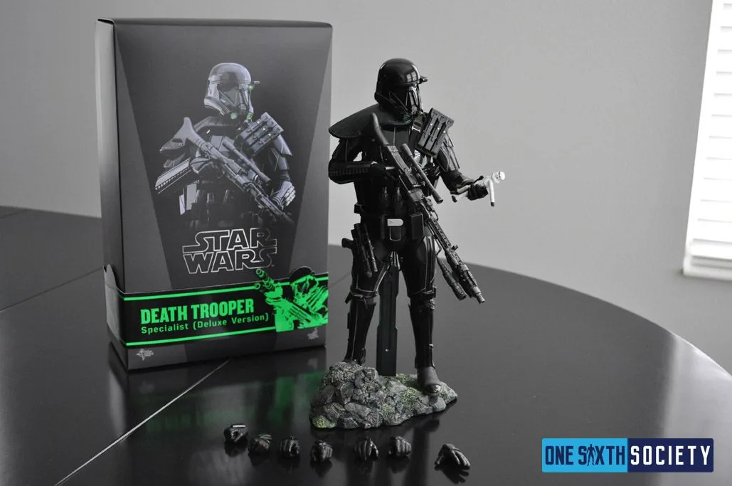 Death Trooper Specialist Deluxe figure on a rocky base beside its labelled box, with interchangeable hands arranged on the table.