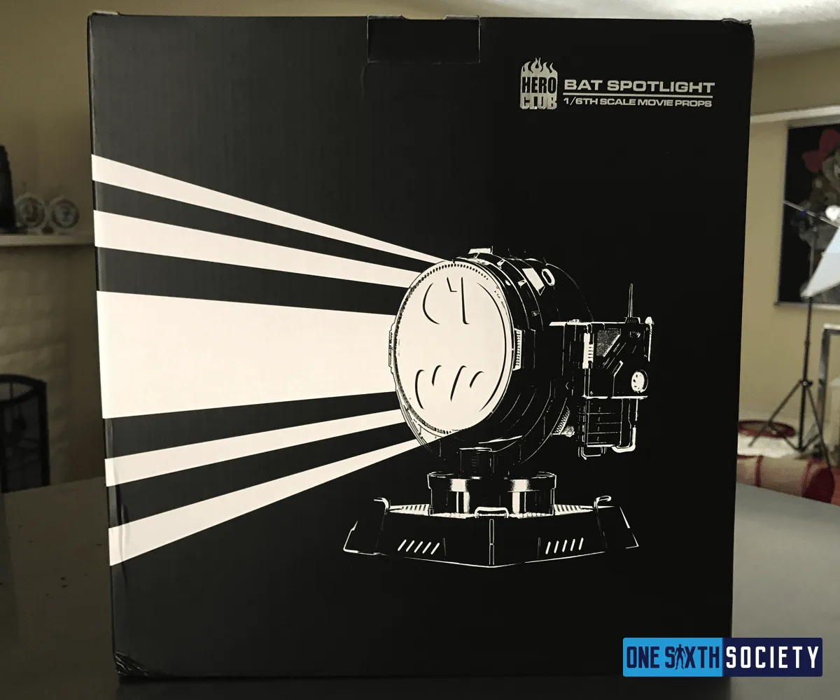 Black Hero Club box with a white searchlight-beam illustration beside the miniature Bat-Signal spotlight.