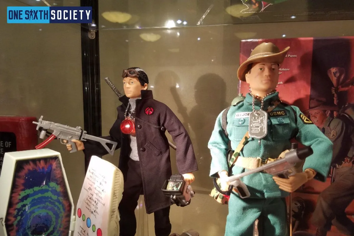 Two G.I. Joe figures in black and teal outfits displayed with weapons and equipment; the teal-clad figure wears a brown hat.
