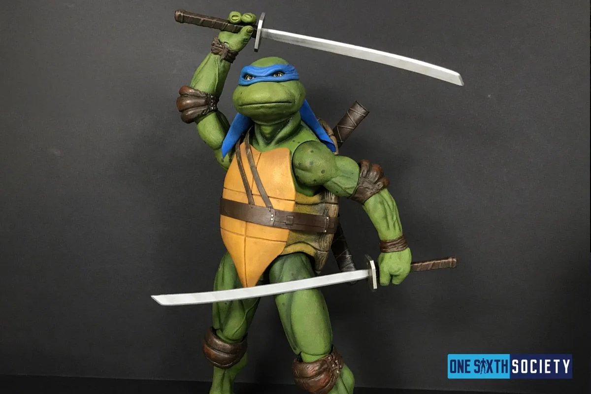 NECA Leonardo standing with one sword raised above his head and the second held horizontally across his waist.