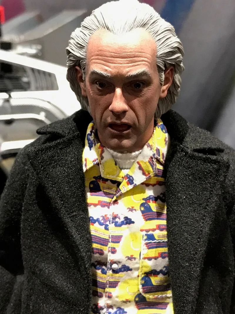 Hot Toys Doc Brown head-sculpt close-up showing swept-back white hair, wide eyes and a partly open mouth above a colorful patterned shirt.
