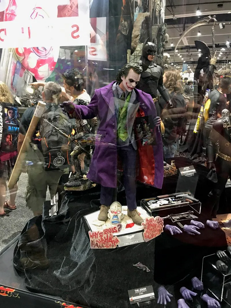 Full Hot Toys Joker display with his purple coat held open, graffiti-marked base and alternate purple-gloved hands laid out beside him.