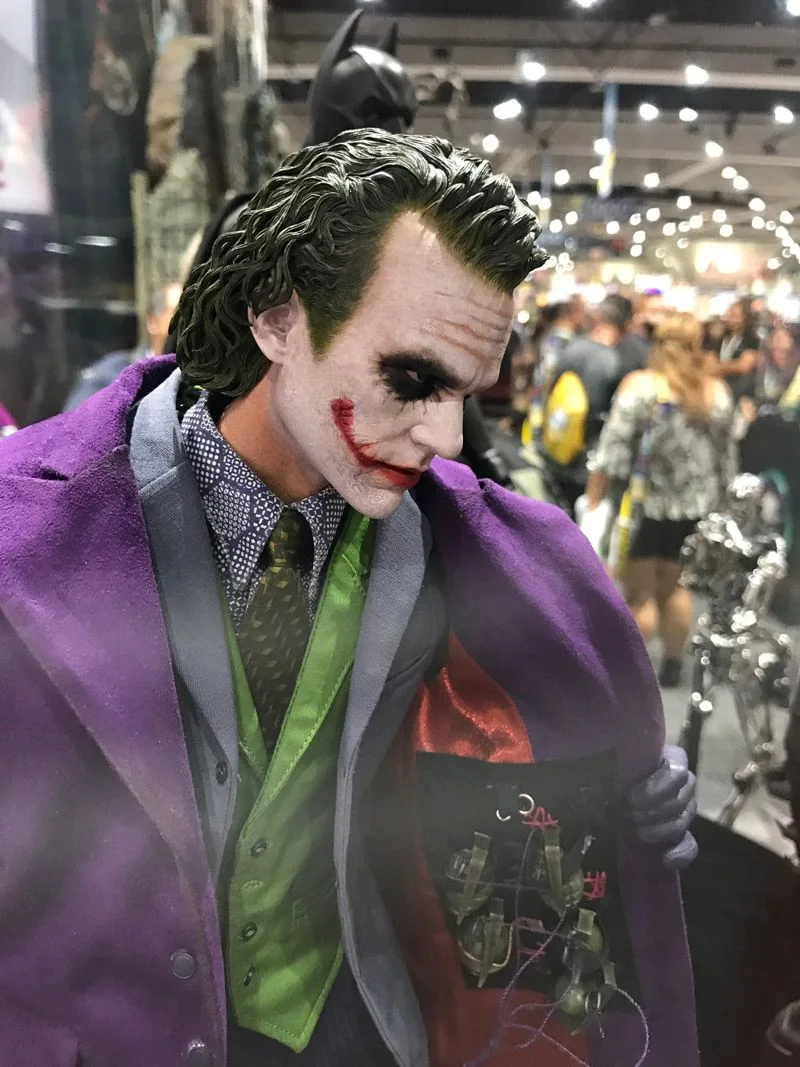 Hot Toys Joker looking downward, with white makeup, green hair and a purple coat opened to reveal grenades beneath its red lining.