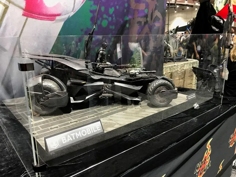 Wide view of the Hot Toys Batmobile in its glass convention display, including the vehicle’s side profile, Batman and a Batmobile nameplate.