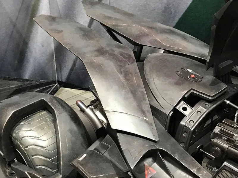 Hot Toys Batmobile detail showing layered angular body panels, hinges and part of a wheel beneath the open cockpit assembly.