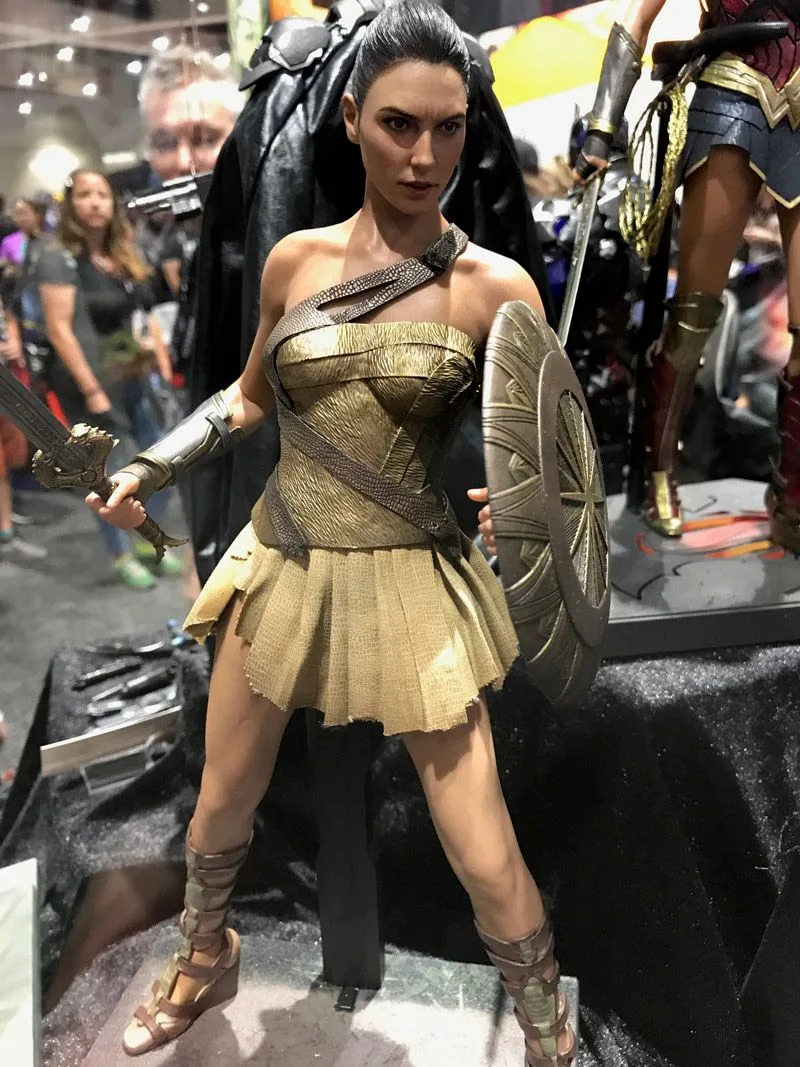 Hot Toys Wonder Woman with tied-back hair, gold training armor and a short skirt, holding a sword and sunburst-pattern shield.