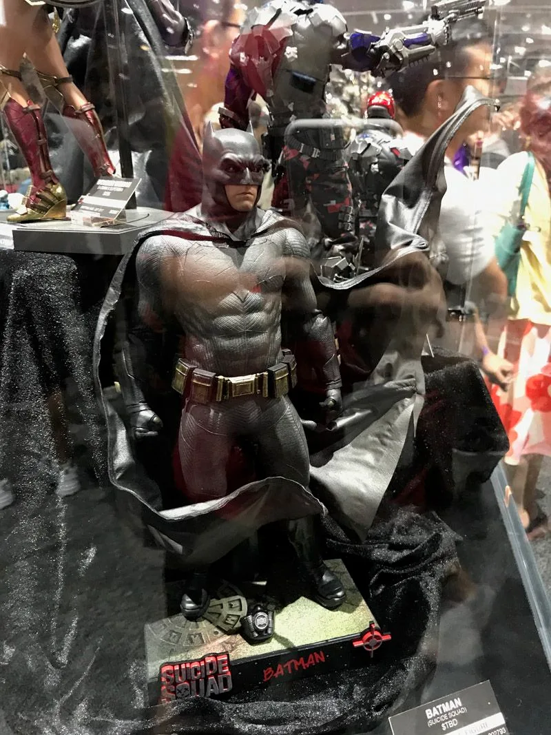 Hot Toys Batman in a gray suit, displayed with his black cape swept outward above a Suicide Squad-branded base.