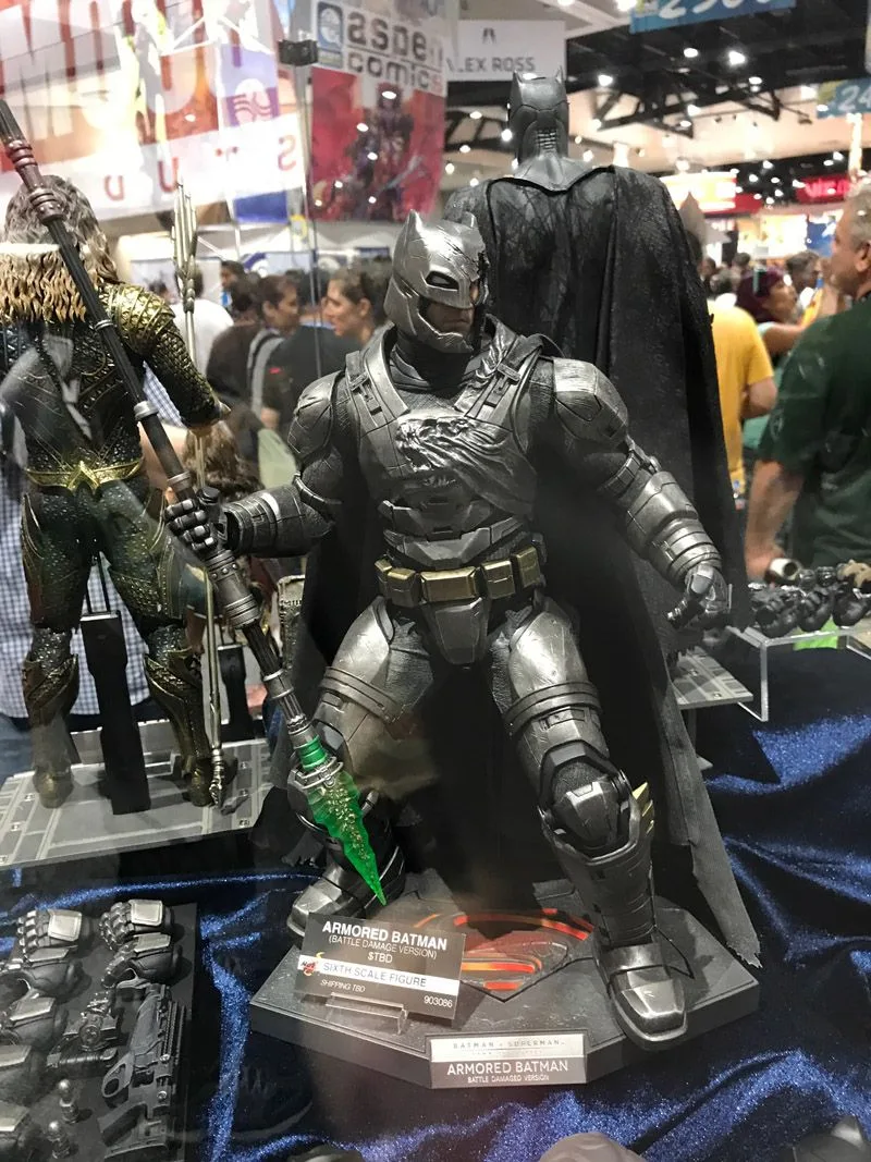 Hot Toys Armored Batman standing wide-legged on a display base and holding a long spear with a translucent green tip.