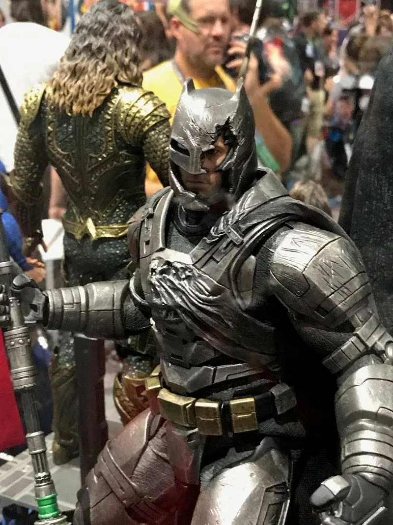 Hot Toys Armored Batman close-up showing scratched metallic armor and a broken helmet section exposing part of his face.