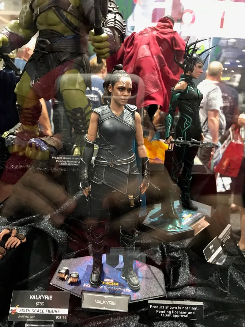 Hot Toys Valkyrie standing on a Thor: Ragnarok display base, with alternate hands beside her and Hela and Gladiator Hulk behind.
