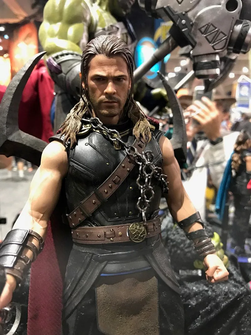 Hot Toys long-haired Thor wearing dark sleeveless armor, crossed straps and a chain across his chest.