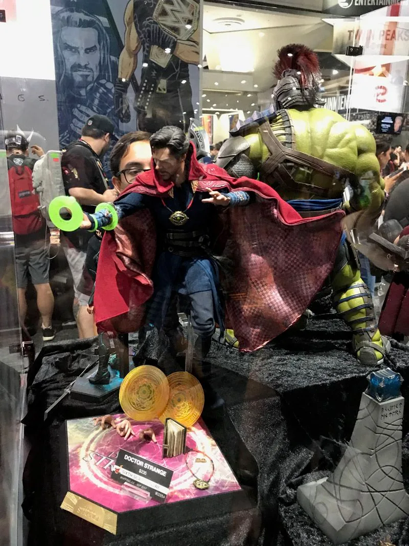 Hot Toys Doctor Strange standing with his red cloak spread wide, green spell effects at one hand and a yellow magic disc near the base.