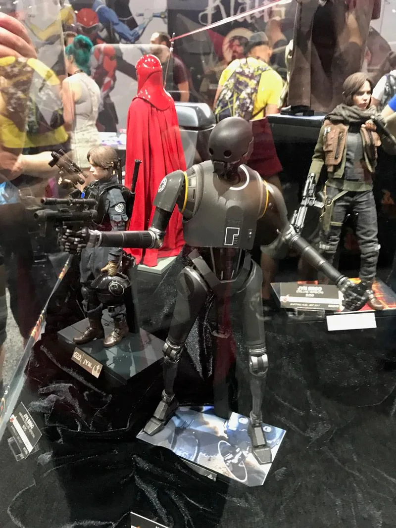 Hot Toys K-2SO standing with long mechanical arms extended, surrounded by Rogue One figures and a red Imperial Royal Guard.