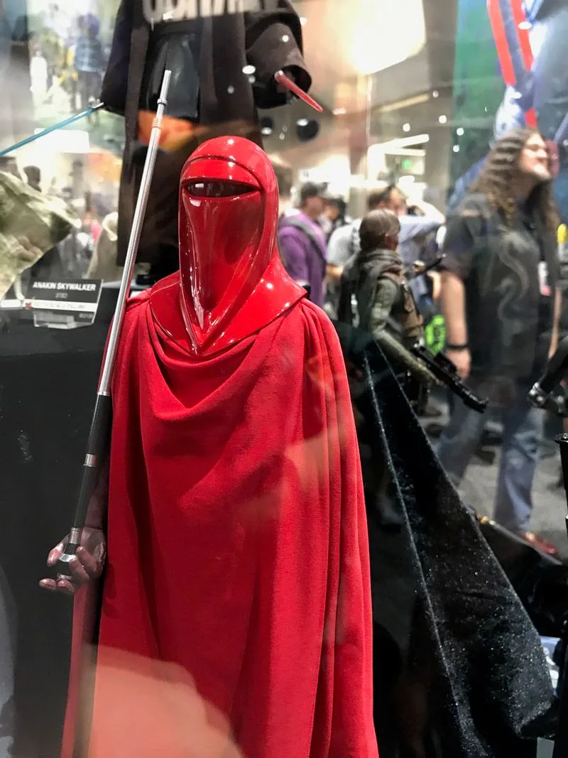 Hot Toys Imperial Royal Guard wearing a glossy red helmet and long red robes, holding a staff upright.