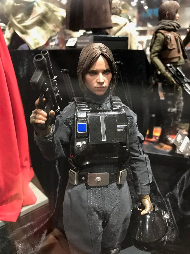Hot Toys Jyn Erso in a dark Imperial disguise, holding a blaster upright in one hand and a black helmet in the other.