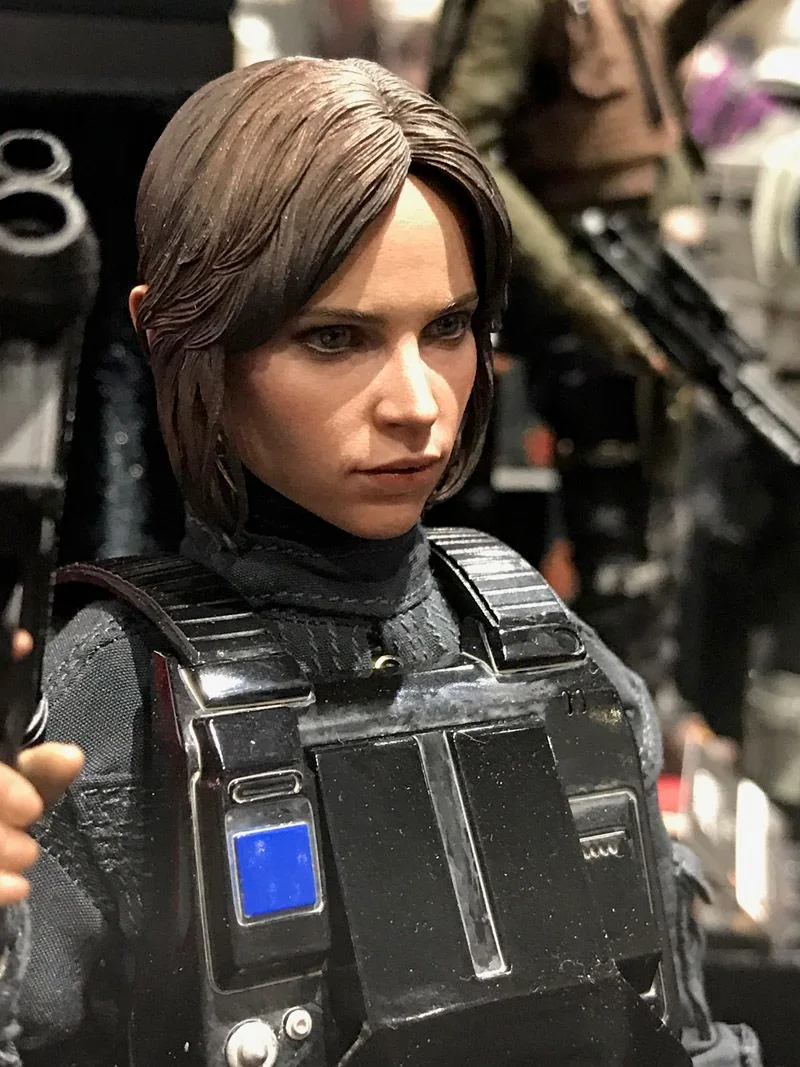 Hot Toys Jyn Erso close-up with brown hair and dark Imperial disguise armor featuring a blue rectangular chest detail.