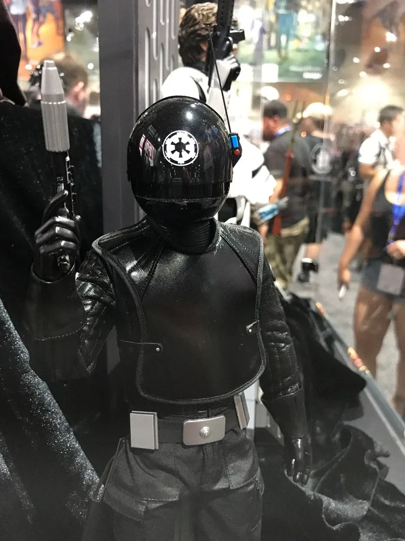 Hot Toys Death Star Gunner upper-body detail showing the white Imperial emblem on his black helmet and a raised blaster.