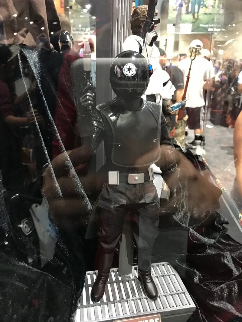 Hot Toys Death Star Gunner in an all-black uniform and enclosed helmet, holding a blaster upright on a grated base.
