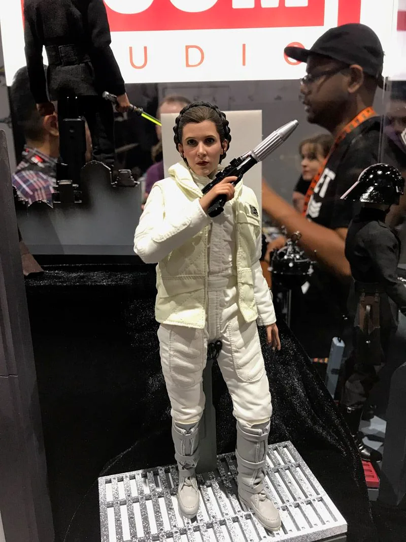 Hot Toys Princess Leia in a white padded Hoth outfit and braided hairstyle, holding a blaster near her shoulder on a grated display base.