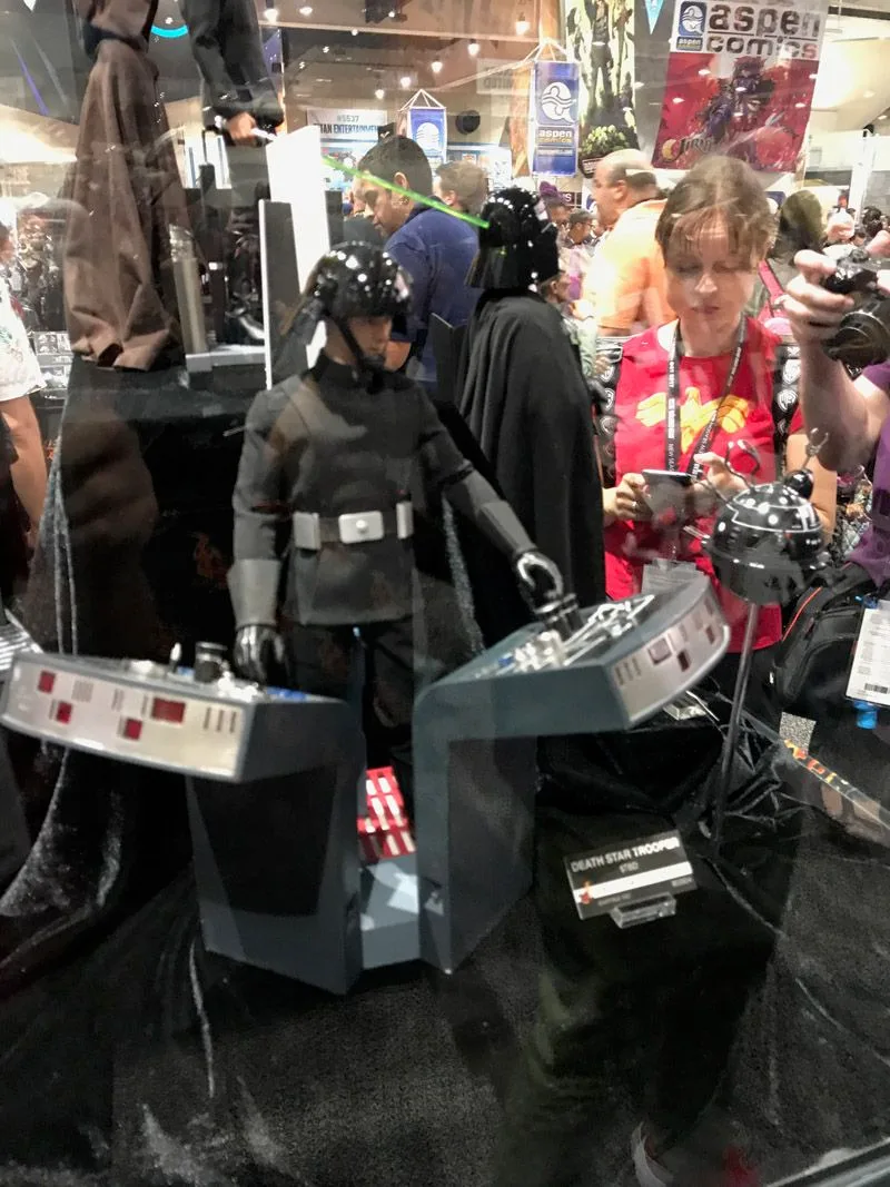 Angled view of the Hot Toys Death Star Trooper and paired gray consoles with red and white controls in the glass display.