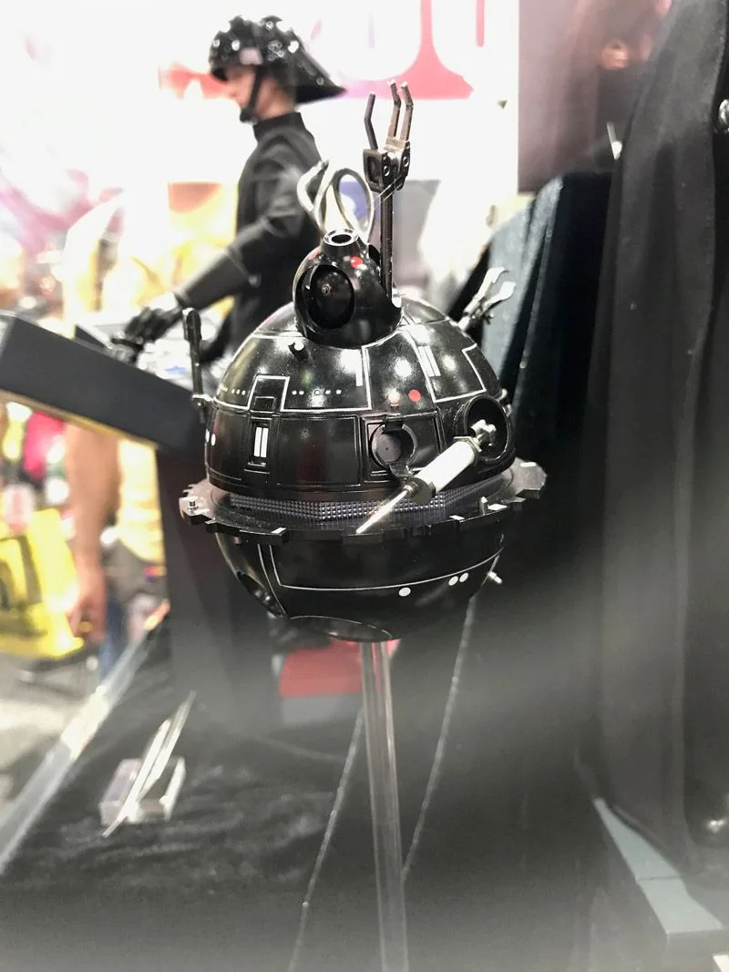Black spherical Star Wars interrogation droid in the Hot Toys display, with small mechanical tools projecting from its shell and a clear support beneath.