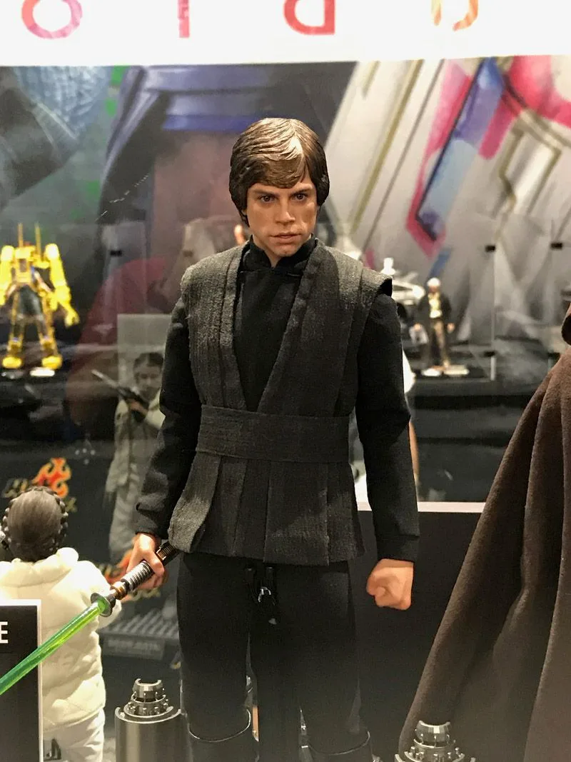 Hot Toys Luke Skywalker in a black Jedi tunic and belt, holding a green lightsaber at his side.