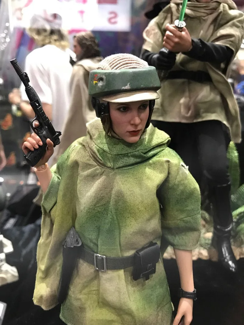 Hot Toys Endor Leia upper-body view showing her helmet, mottled green poncho, black belt and raised blaster.