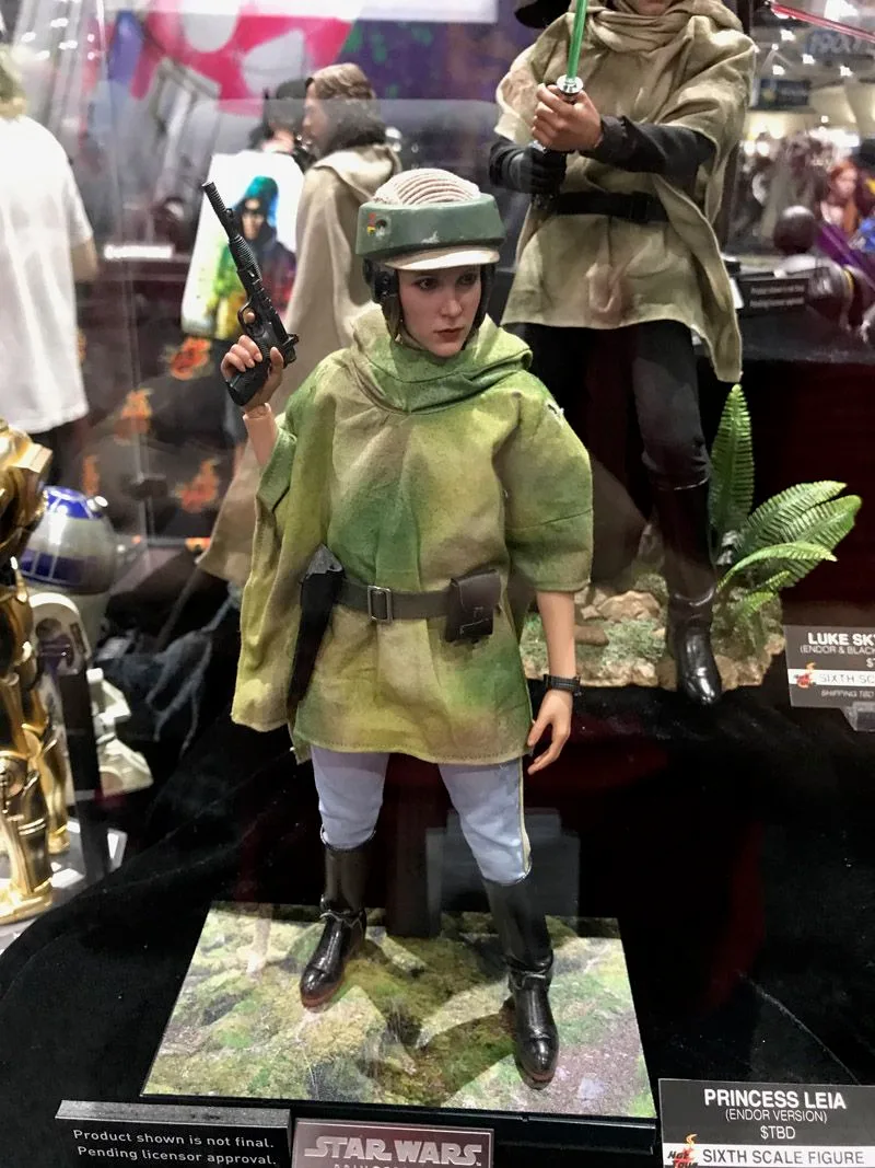 Hot Toys Princess Leia wearing an Endor helmet and green camouflage poncho, holding a blaster on a mossy forest-style base.