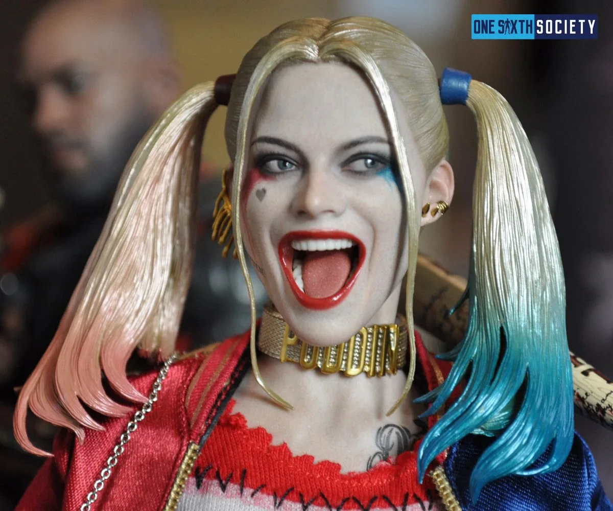 Harley Quinn head sculpt with an open red-lipped smile, pink-and-blue pigtail ends, mismatched eye makeup and a cheek heart tattoo.