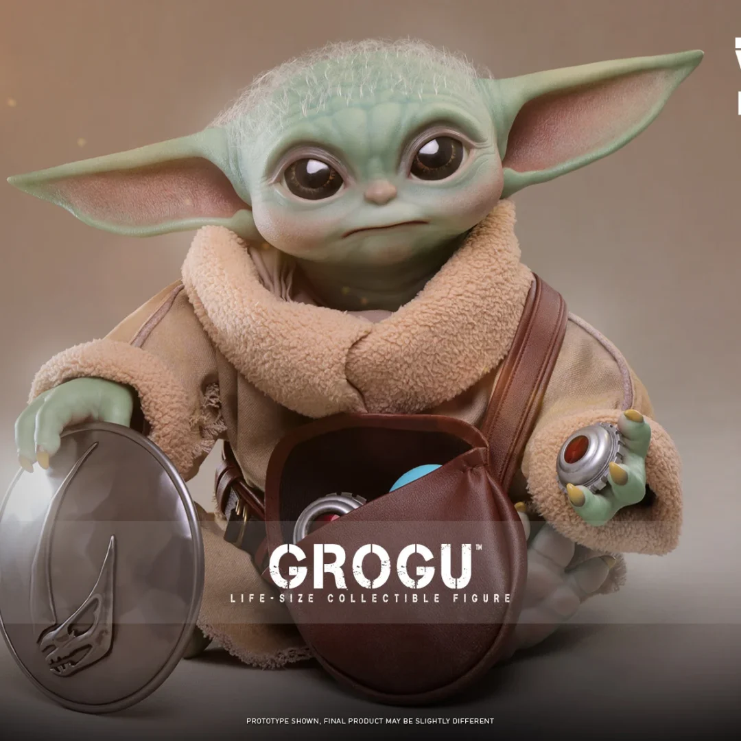 Hot Toys Grogu seated with an open brown pouch, one hand on the detached silver chest plate and the other holding a red-centered grav charge.