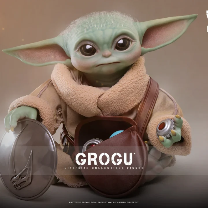 Hot Toys Grogu seated with an open brown pouch, one hand on the detached silver chest plate and the other holding a red-centered grav charge.