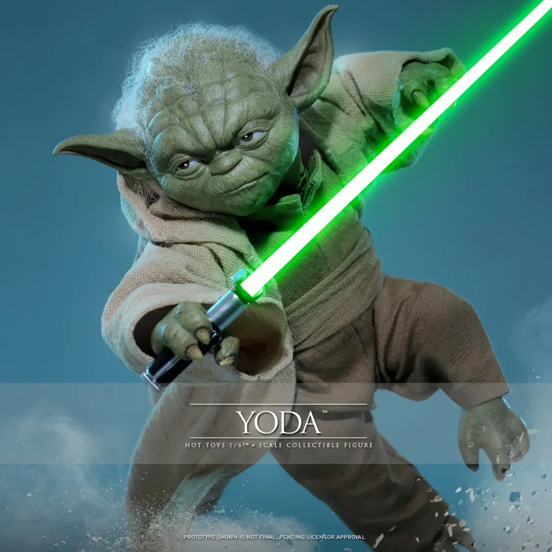 Hot Toys Yoda lunging through the air with a green lightsaber across his body, gray-white hair above his determined face and beige robe swept aside.
