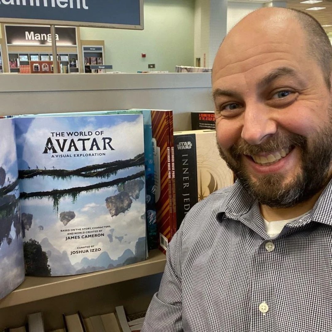 Joshua Izzo smiling beside The World of Avatar: A Visual Exploration in a bookstore