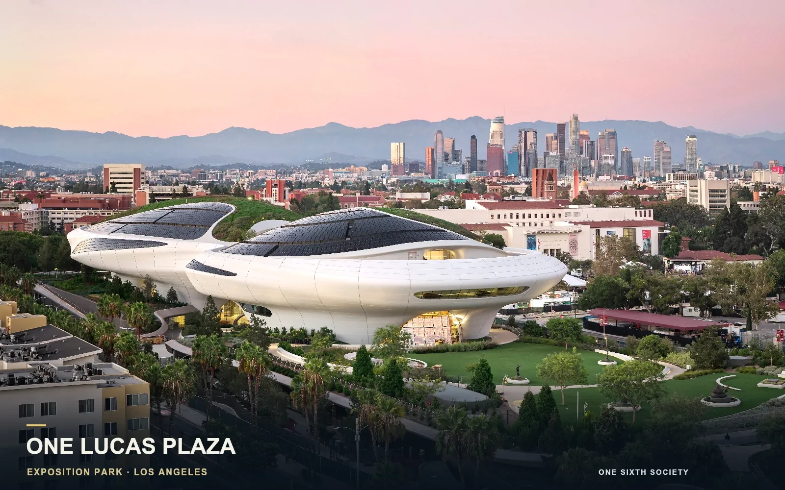 Lucas Museum exterior in Exposition Park beneath a pink evening sky, with landscaped paths in front and downtown Los Angeles behind.